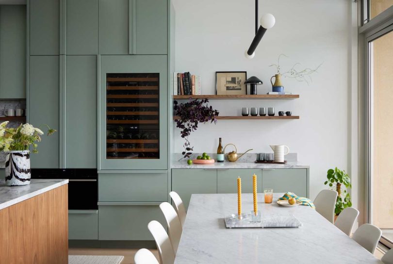apartment interior with view of modern kitchen in pale green and dining room