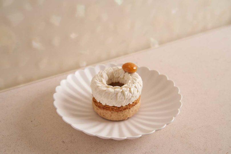angled down view of rippled white plate holding a donut-like pastry