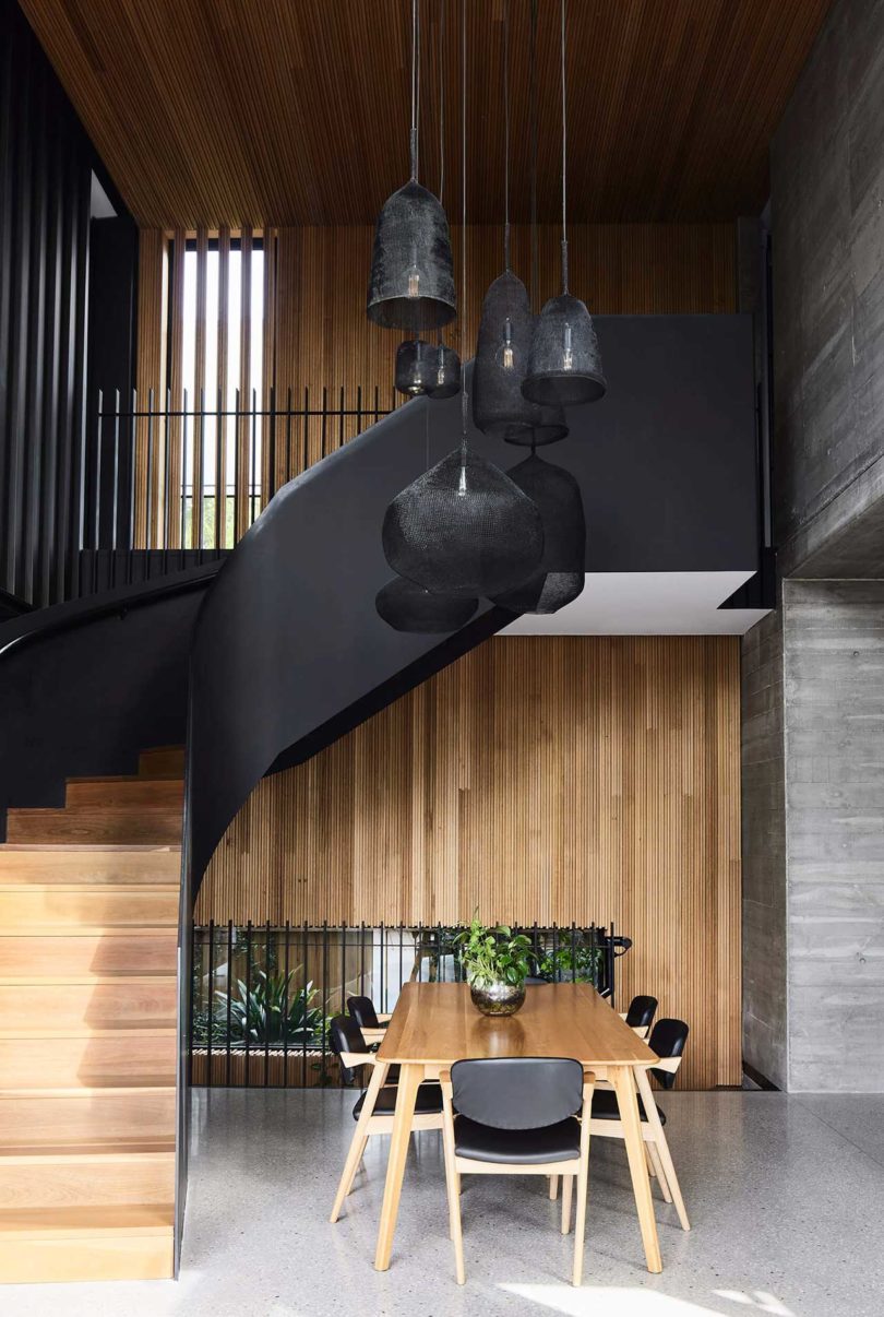 modern home interior with curved black staircase and wooden table