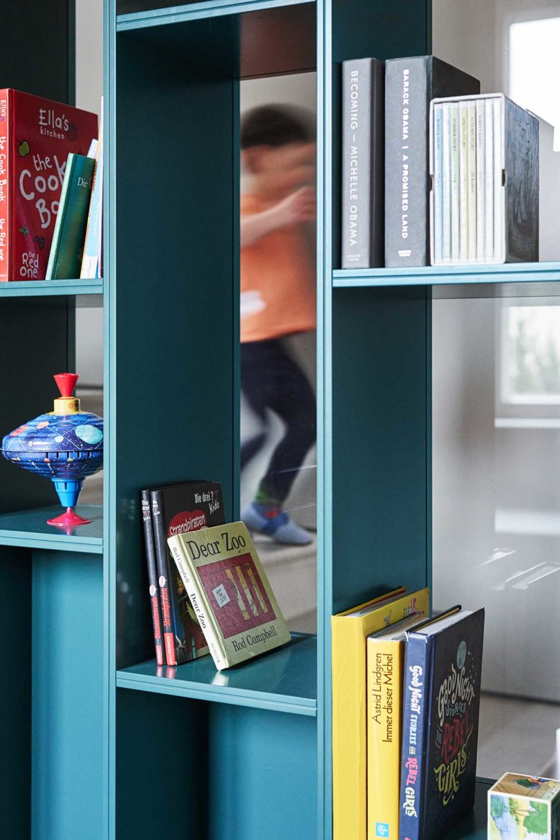 Nahaufnahme des grünen/blauen modernen Bücherregals mit Stapel Büchern