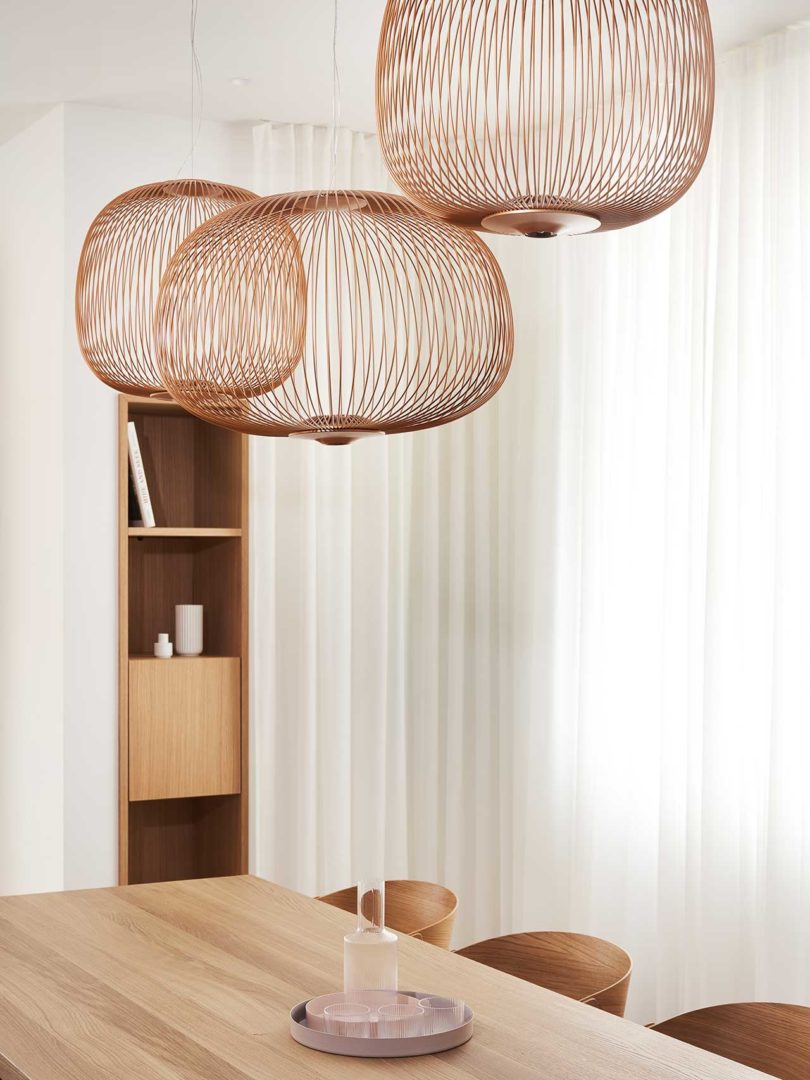 interior of modern home with wooden details and dining table with copper wire pendants