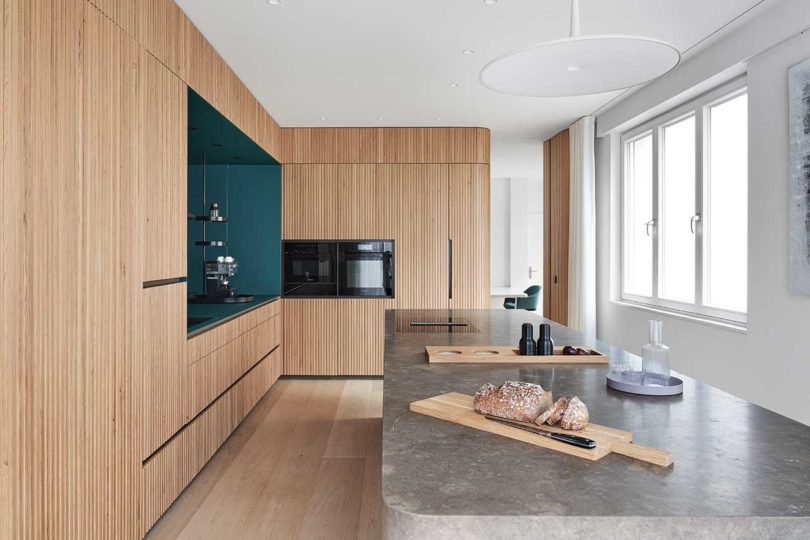 interior shot of modern kitchen with wood slat details and dark green cabinet cutout