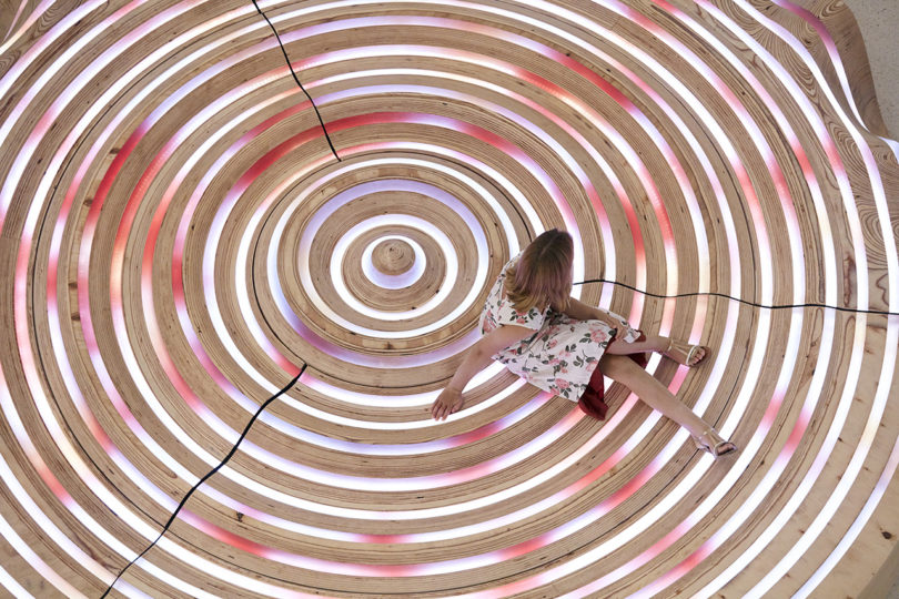 woman interacting with a circular installation in a building's lobby