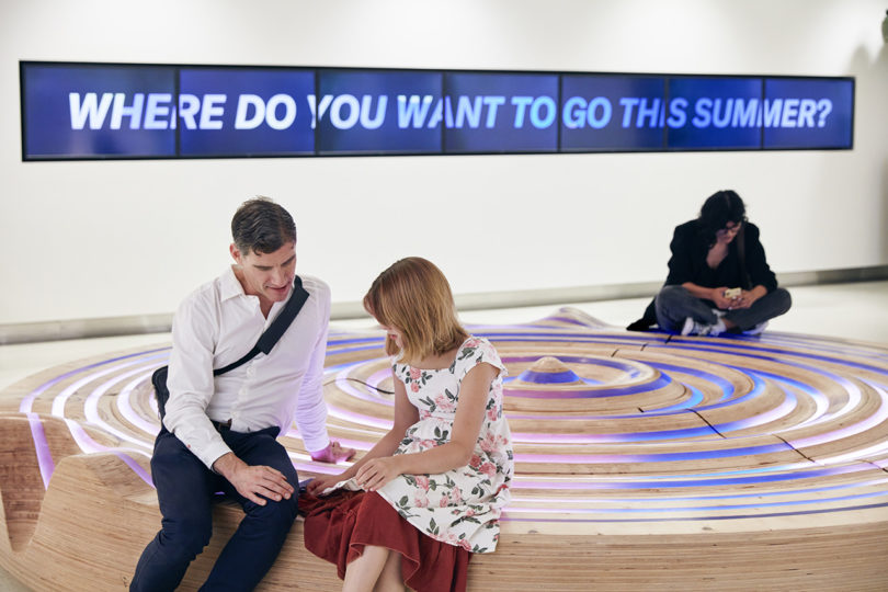 people interacting with a circular installation in a building's lobby
