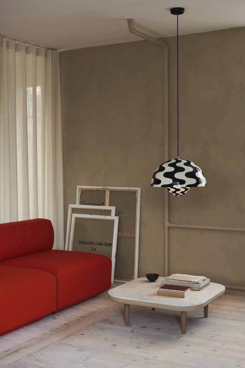black and white wavy pendant light in living room with red sofa