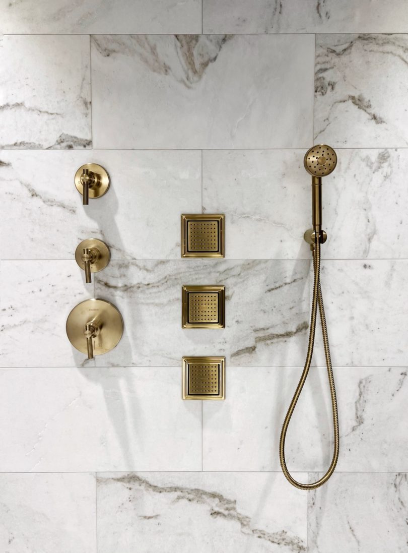 gold bath fixtures on marble wall