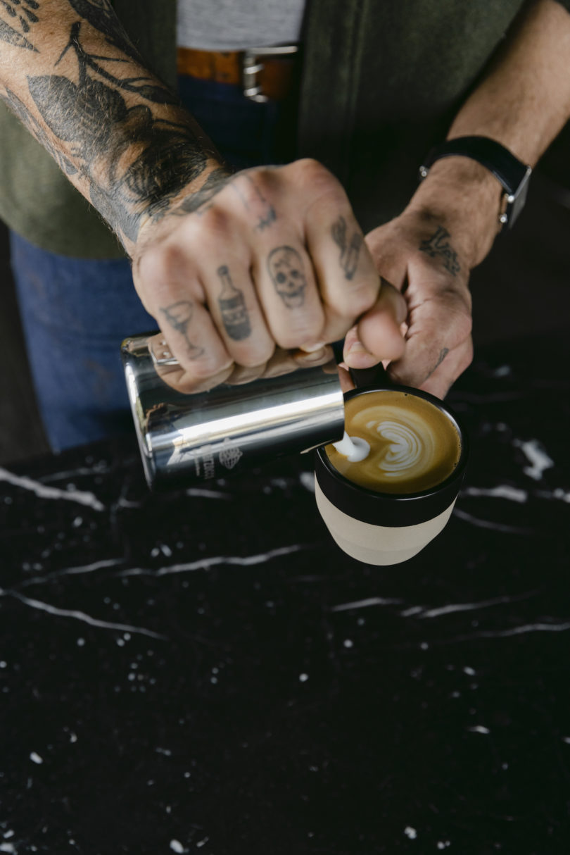 hands making latte art in coffee cup