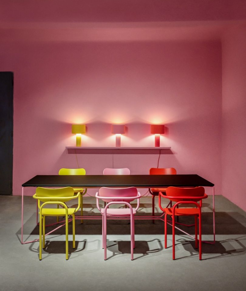 yellow, pink, and red armchairs around a dining table