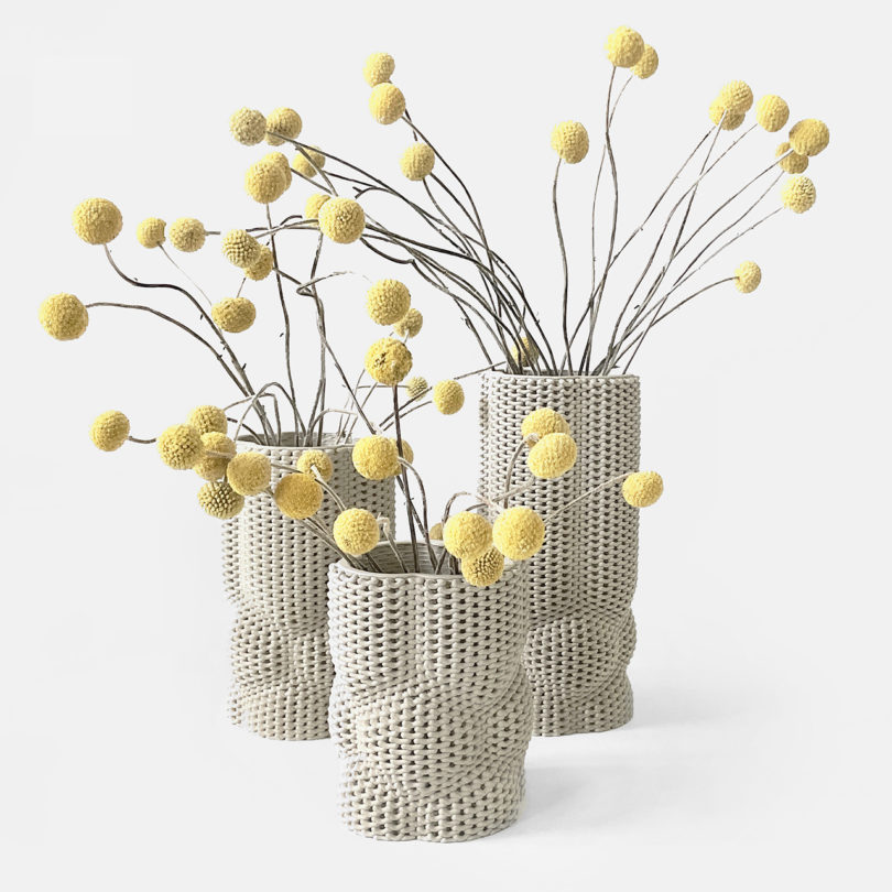three white 3D printed vases with flowers on a white background