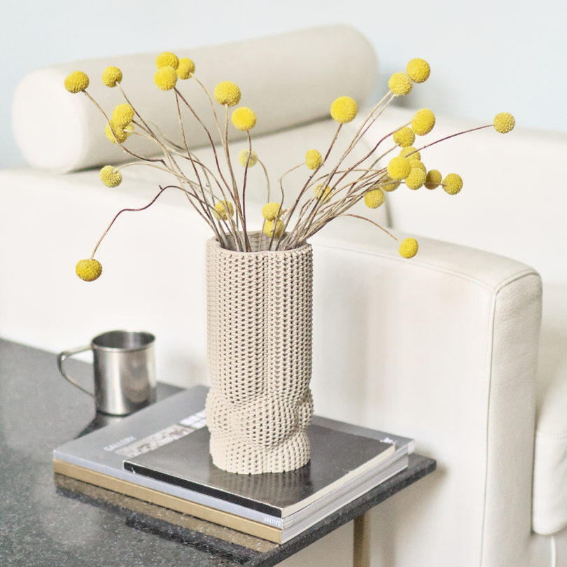 white 3D printed vase with yellow ball-shaped flowers on a side table