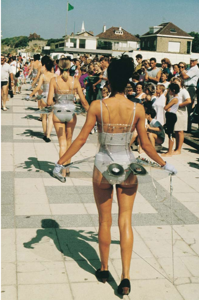 the back of a single file parade of women wearing see-thru tutus