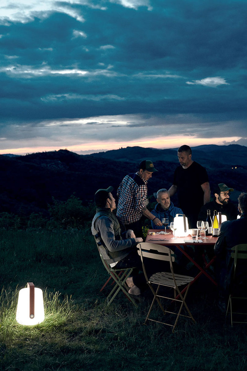 people gather around an outdoor dining set with LED lanterns