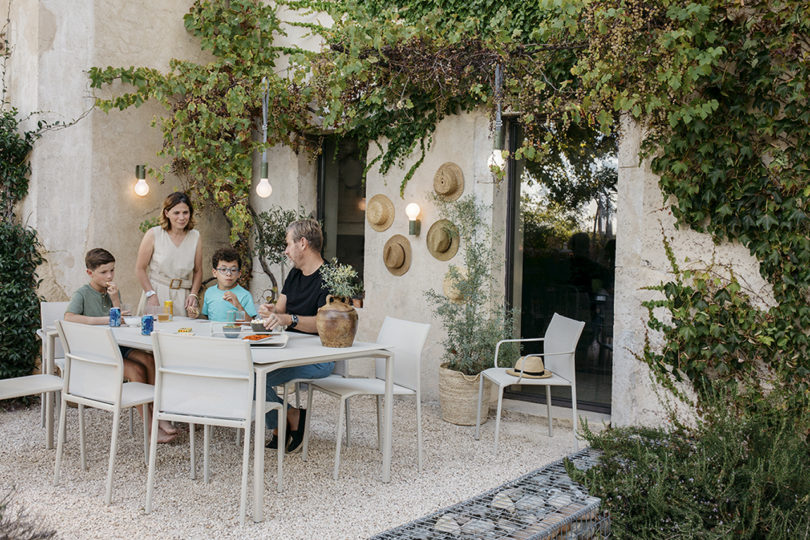 styled white outdoor dining furniture beside a pool with people