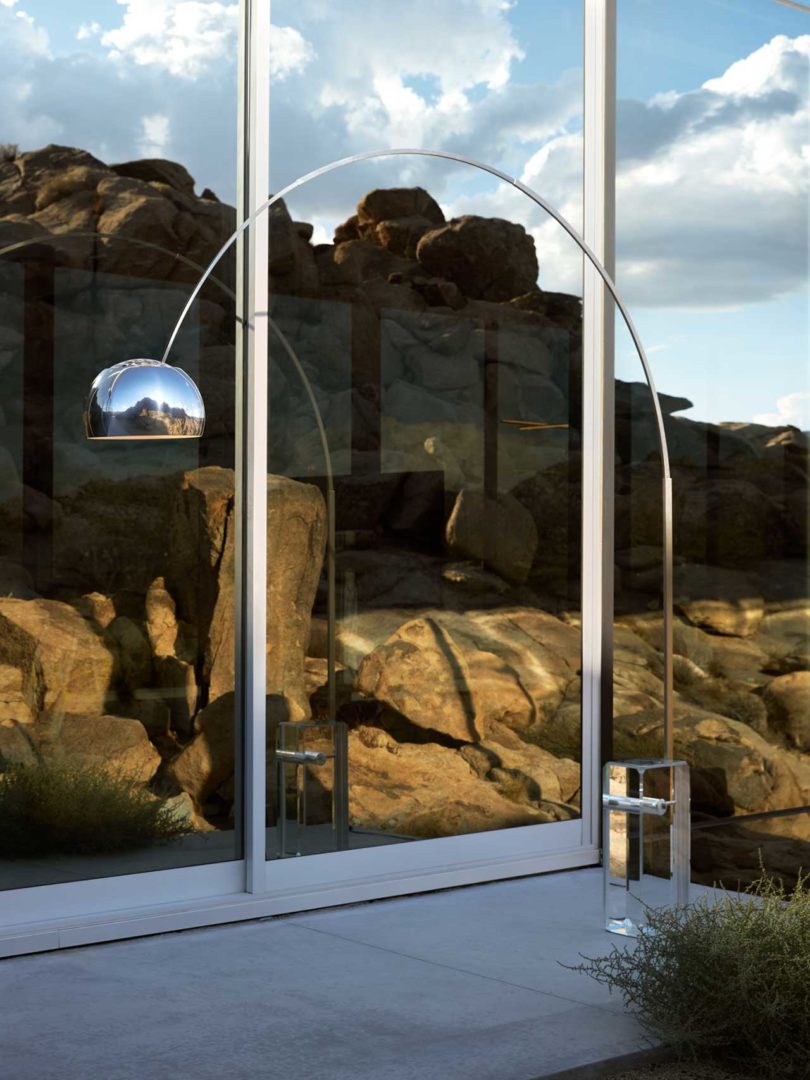 corner interior view of modern house with arched chrome lamp and desert landscape beyond