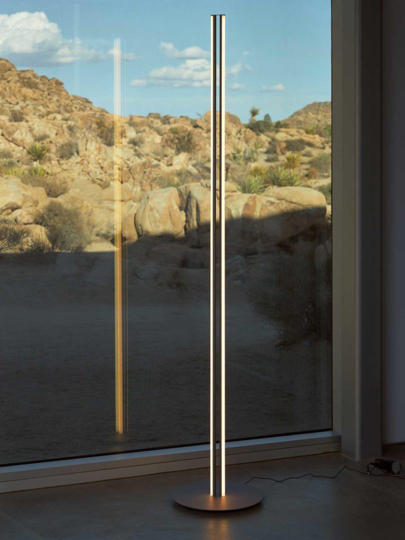 tall narrow floor lamp in front of window with rocky landscape beyond