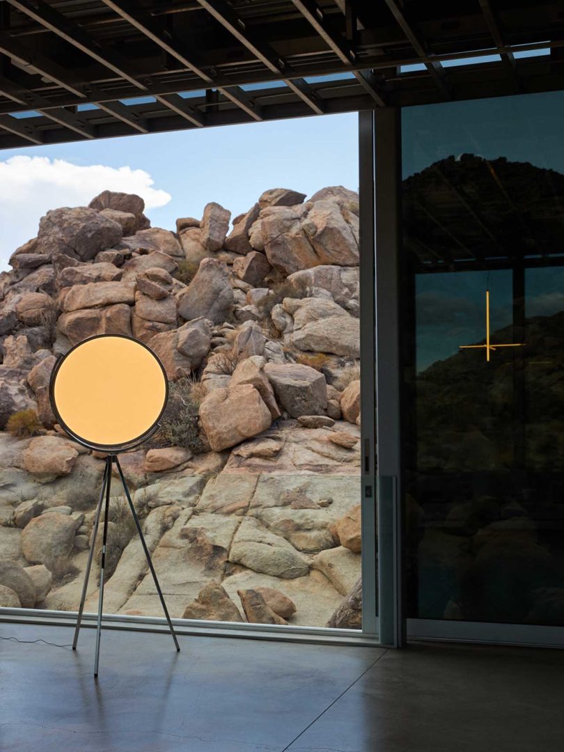 modern tripod lamp in modern house in front of window with rocky landscape beyond