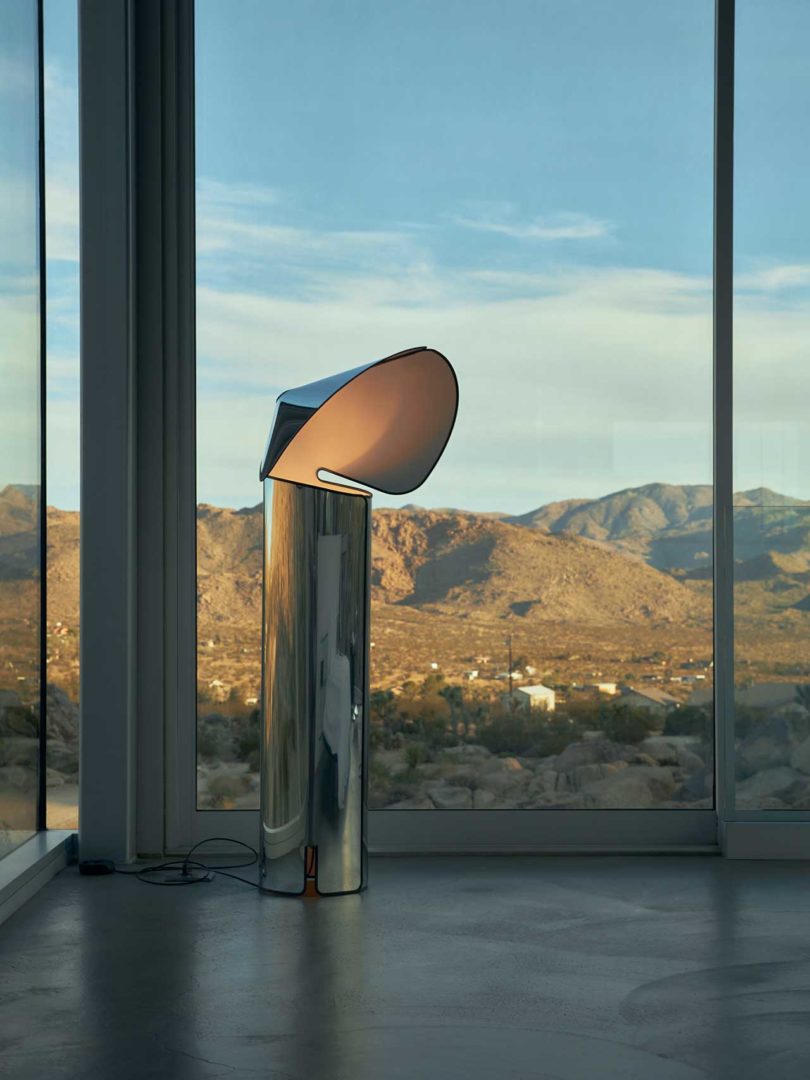 modern interior shot with chrome floor lamp in front of window with rocky landscape beyond