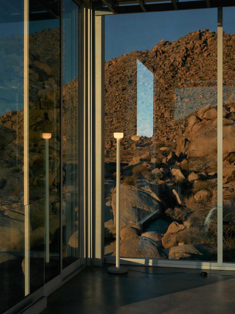 فضای داخلی مدرن با لامپ کف باریک در مقابل پنجره با مناظر صخره ای فراتر