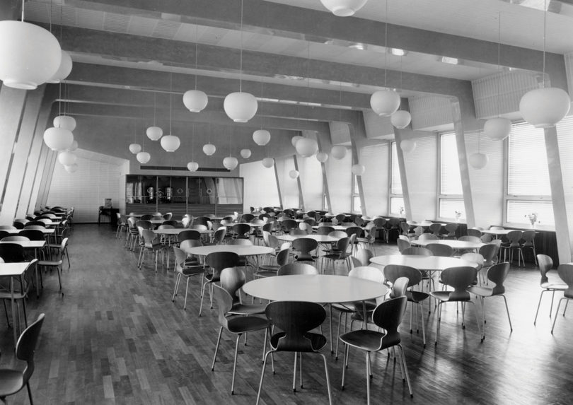 black and white archival image of an indoor dining area with round tables and chairs