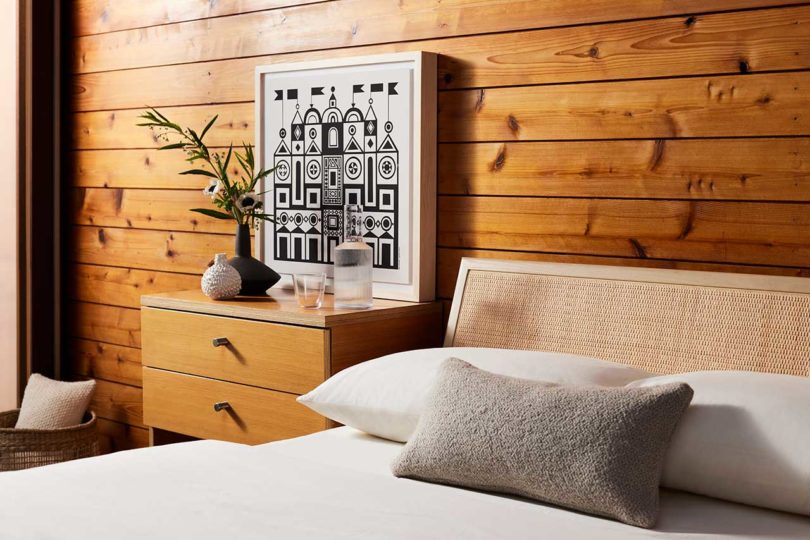 angled shot of modern bedroom with wood paneled wall with black and white castle print hanging