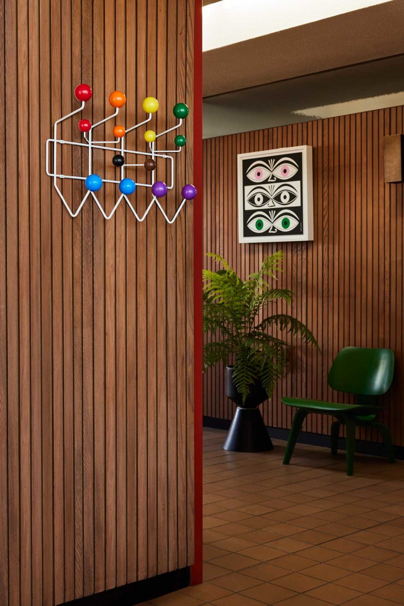modern interior with wood paneled walls with Eames wall hanger and Alexander Girard eye print hanging