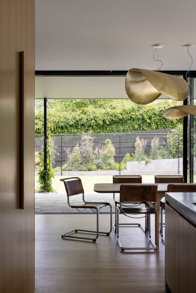 Modern dining room looking out through kitchen to open floor-to-ceiling windows