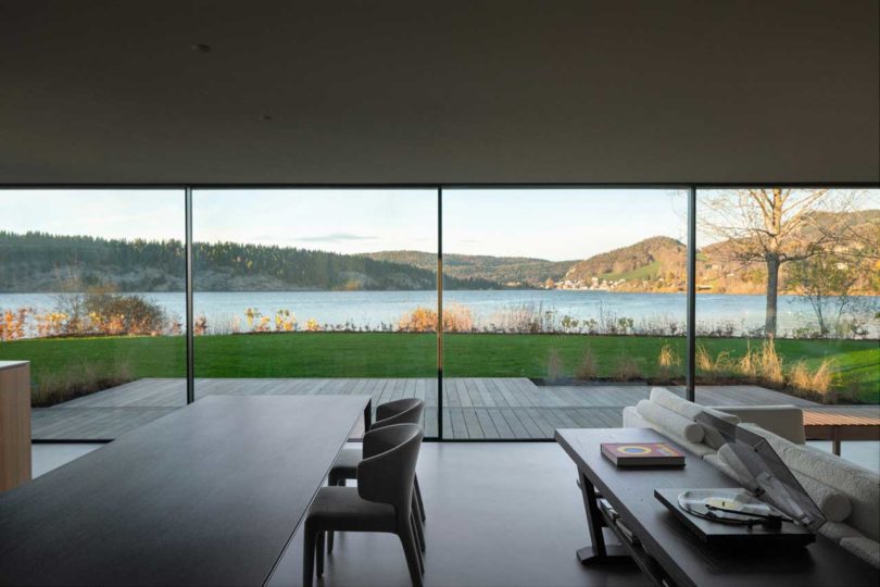 نمای داخلی خانه مدرن با اتاق غذاخوری مینیمالیستی که به دریاچه نگاه می کند