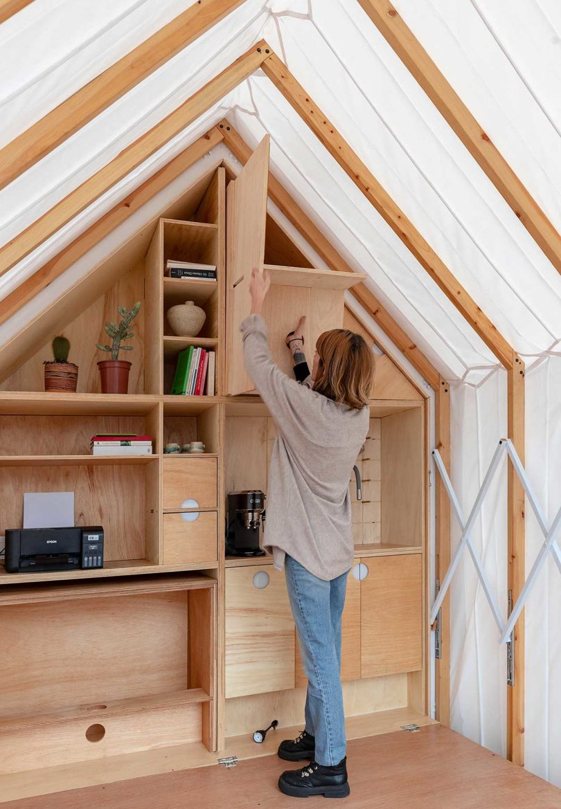 view inside expandable living shelter with woman putting something on shelf