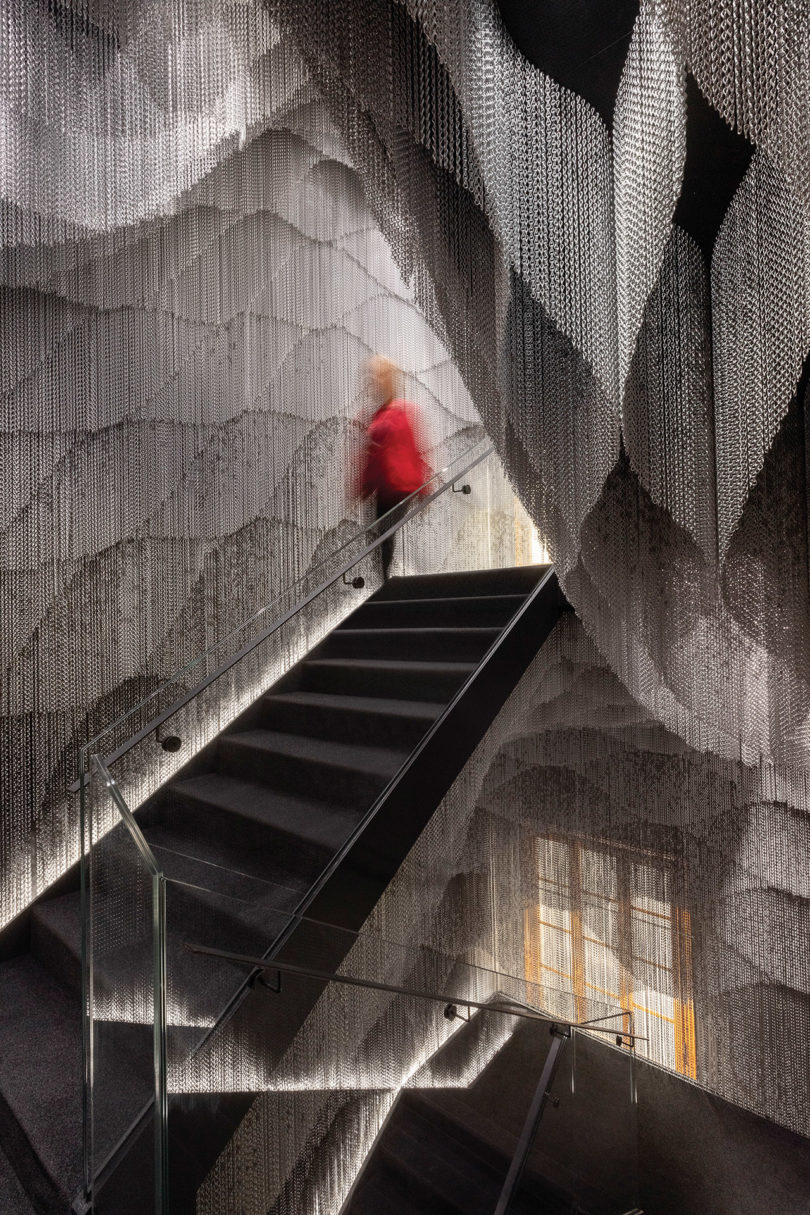 black chain installation with a person in red walking down the stairs in the background