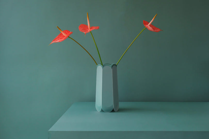 teal hexagonal-shaped vase with red flowers