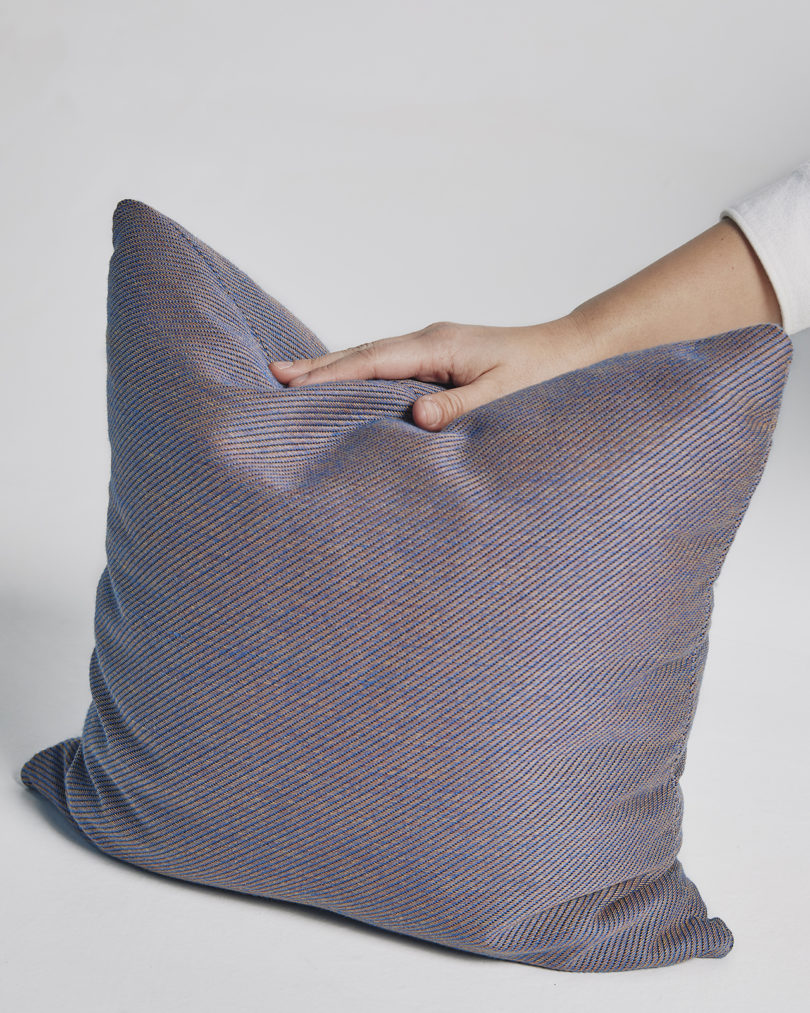 violet square throw pillow with a hand resting on it
