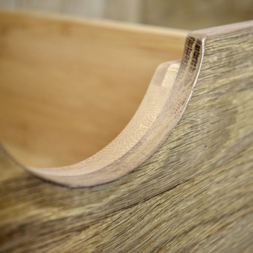 The curve of a wooden drawer recess/handle is in focus with the rest of the drawer out of focus behind