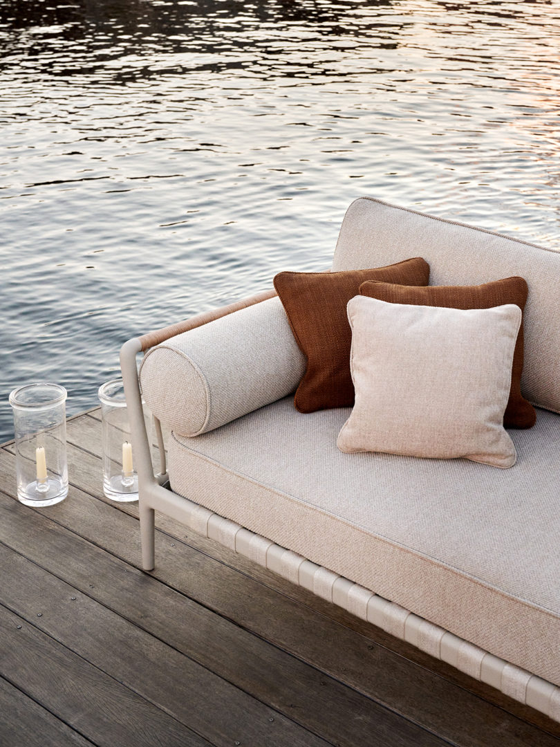 detail of outdoor sofa styled with pillows and candles on a dock