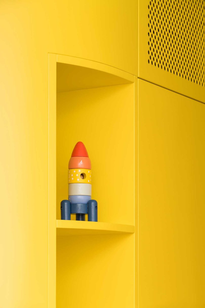 closeup view of modern yellow built-in cabinets with multicolored toy rocket