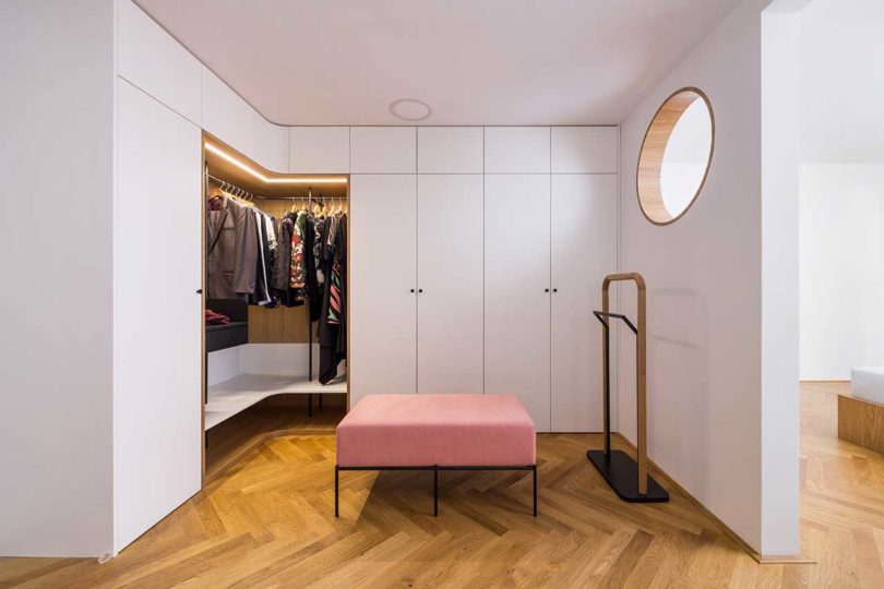 open walk-in closet with pink stool in center