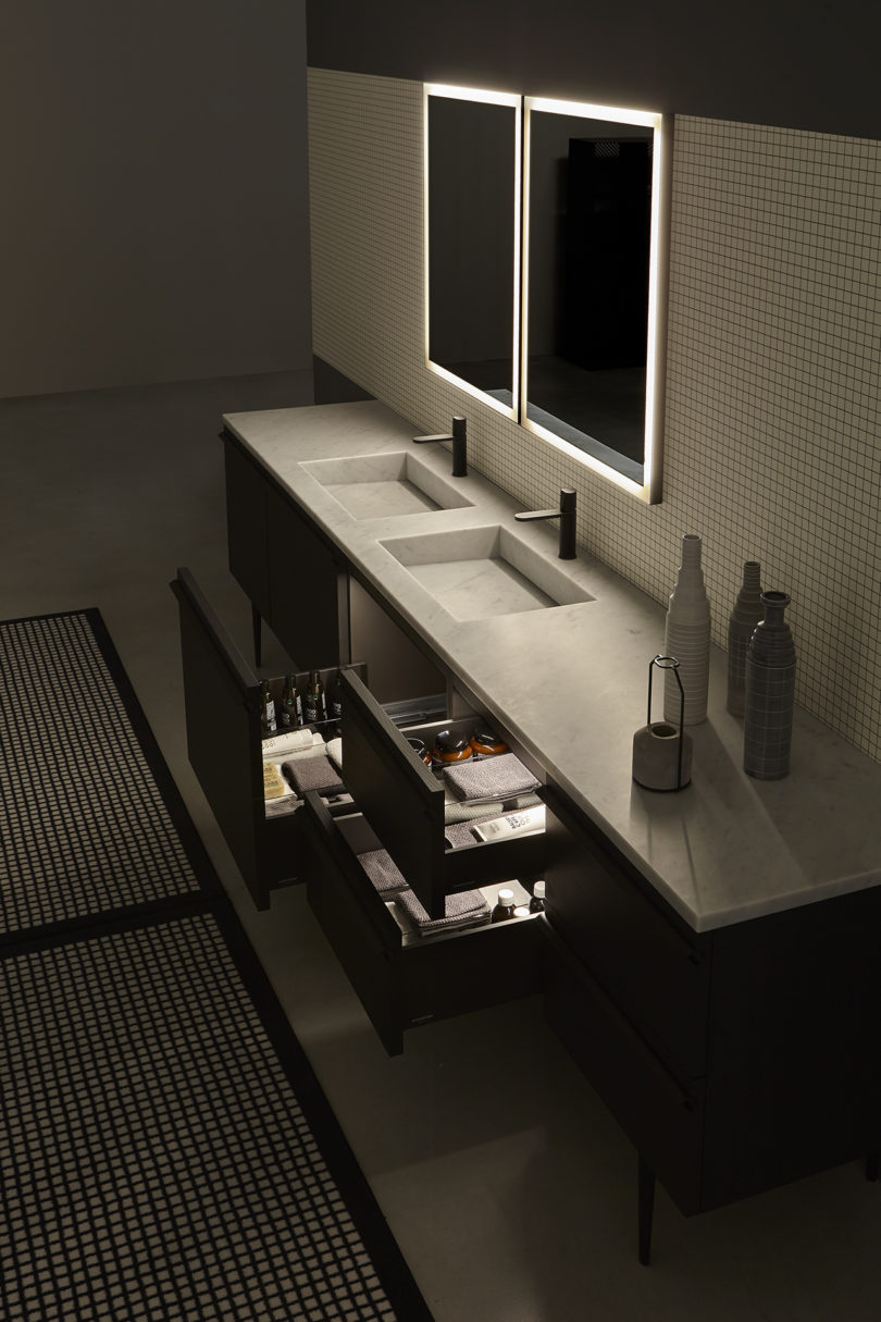 dual bathroom vanity with two illuminated mirrors and an open and illuminated drawer
