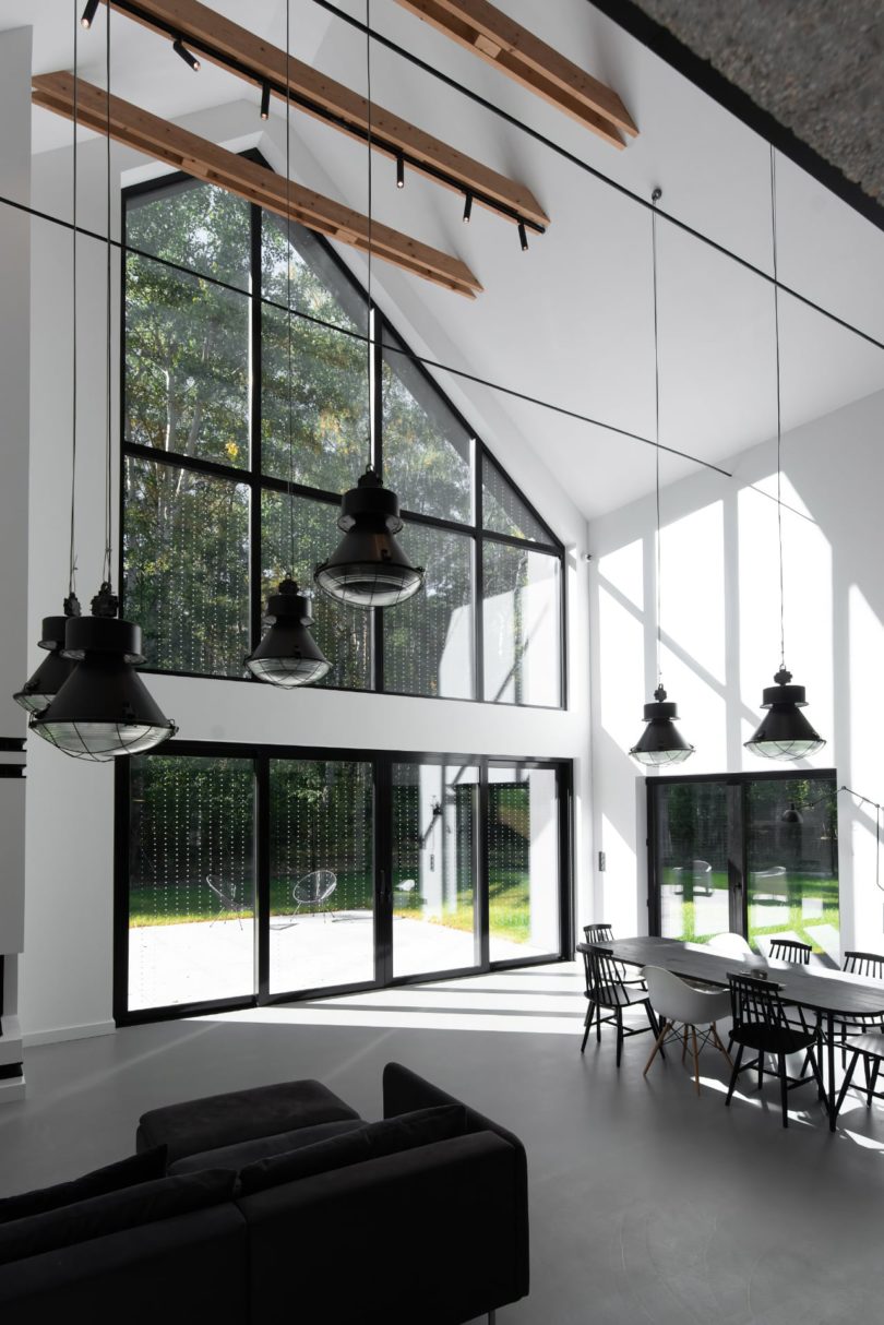 angled interior view of modern living and dining room with double height ceiling