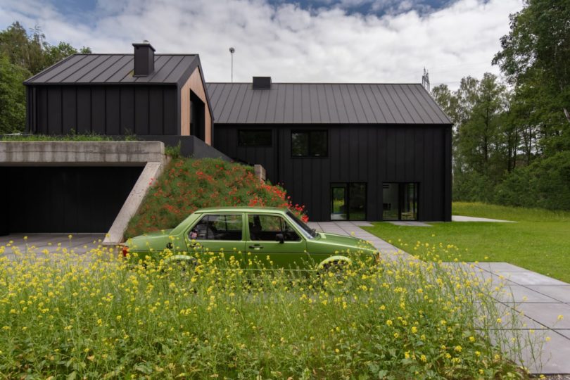 side exterior view of modern black house with green car in front