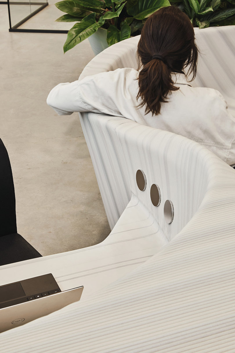 woman sitting on sculptural, white and grey furniture in office lobby