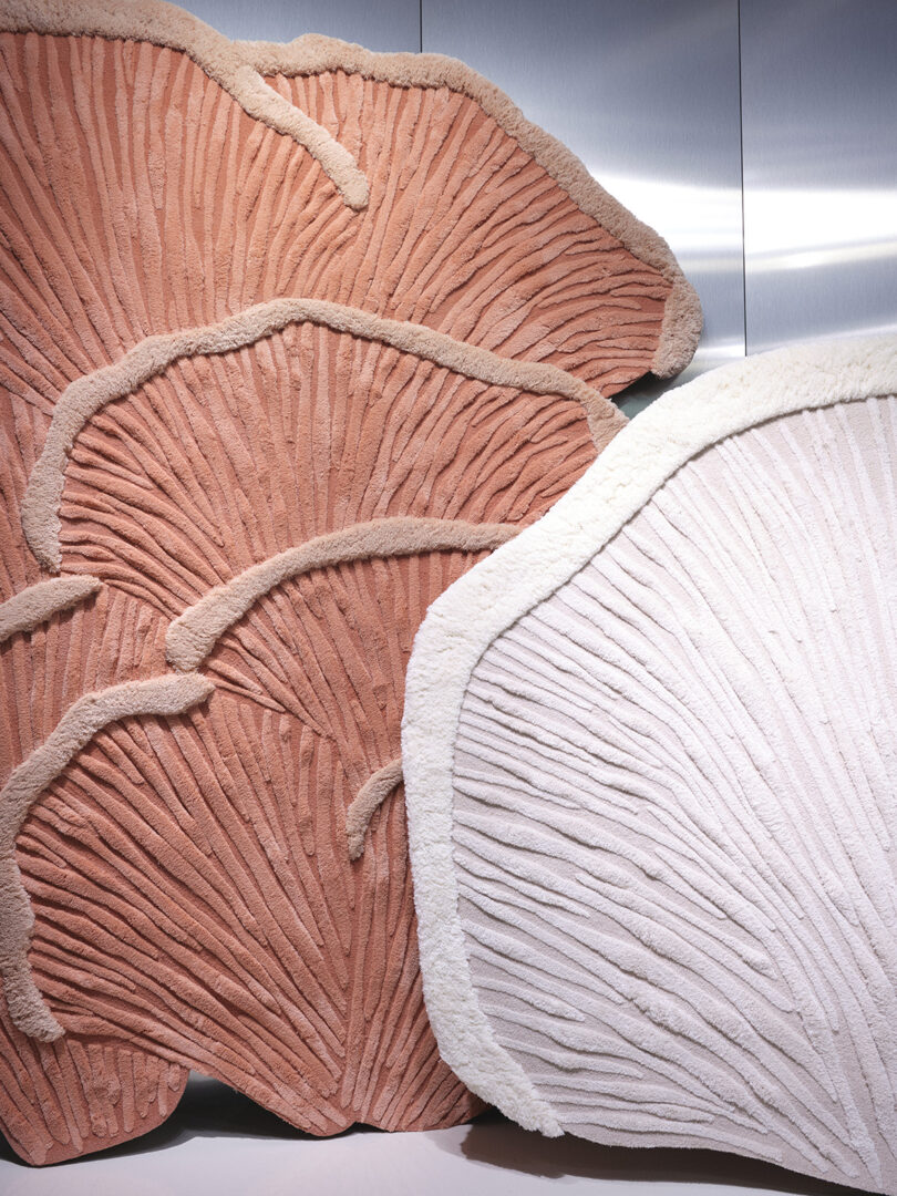 Detail close up shot of pink rug and white rugs designed to resemble underside of oyster mushroom gills in Merino wool.