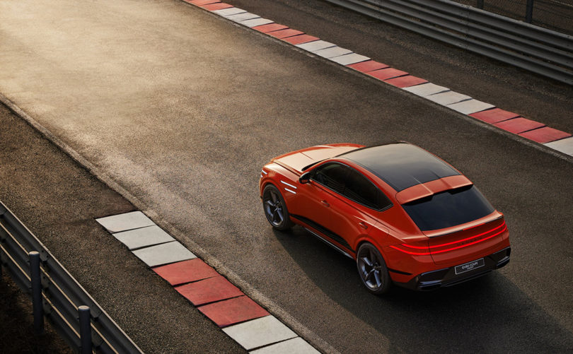 Red orange Genesis GV80 Coupe Concept set on race track from overhead view.