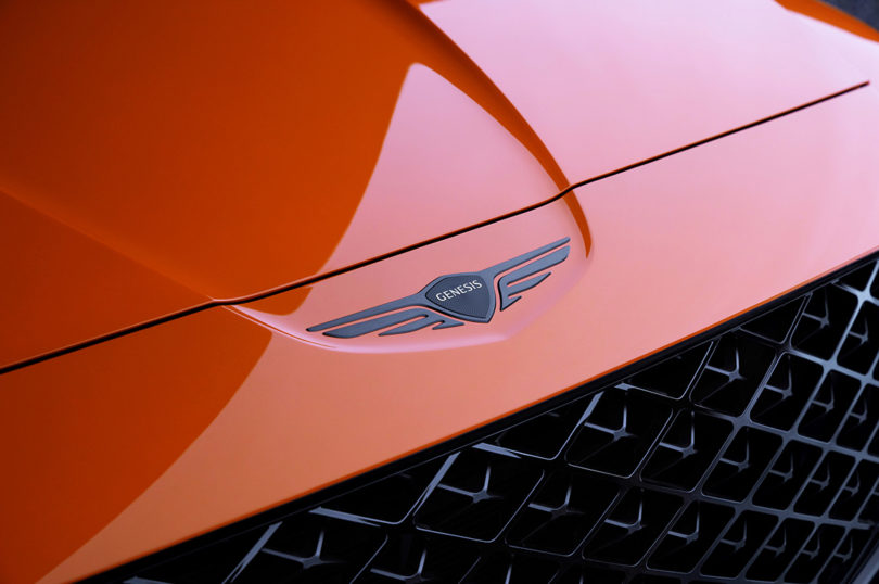 Detail of Genesis emblem on red orange Genesis GV80 Coupe Concept front hood.