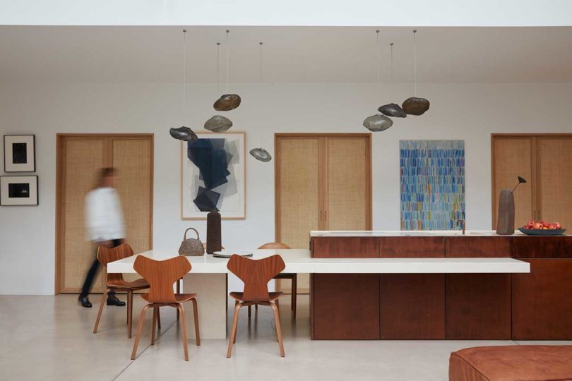 interior view of modern loft apartment looking towards minimalist kitchen with extended island and wood chairs