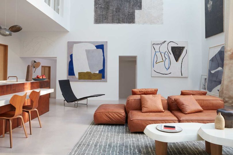 interior view of modern loft apartment living room with modular leather sofa and art covered walls