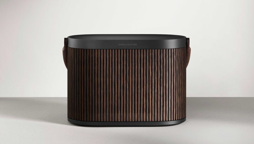 Beosound A5 in black anthracite aluminum with a dark oak wood panel cover.