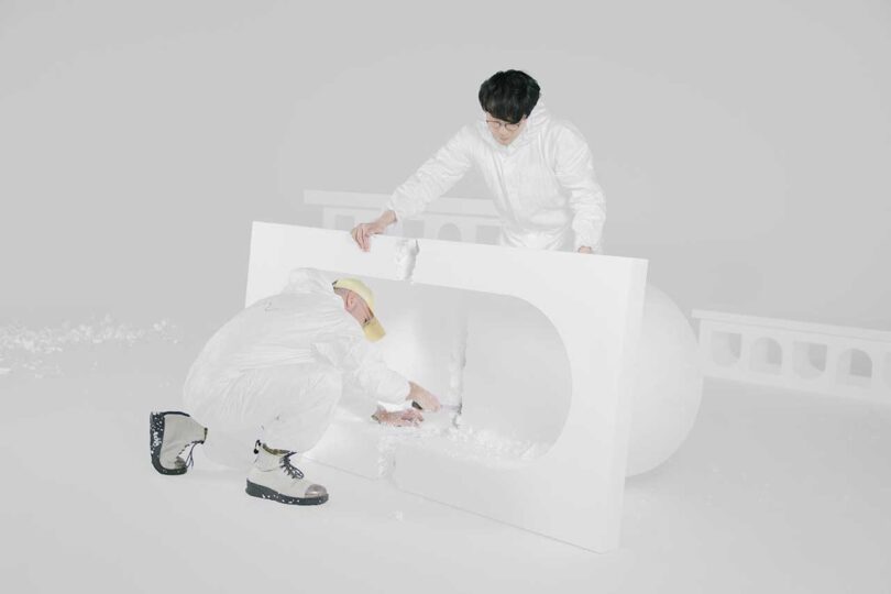 two men bending down breaking white concrete furniture