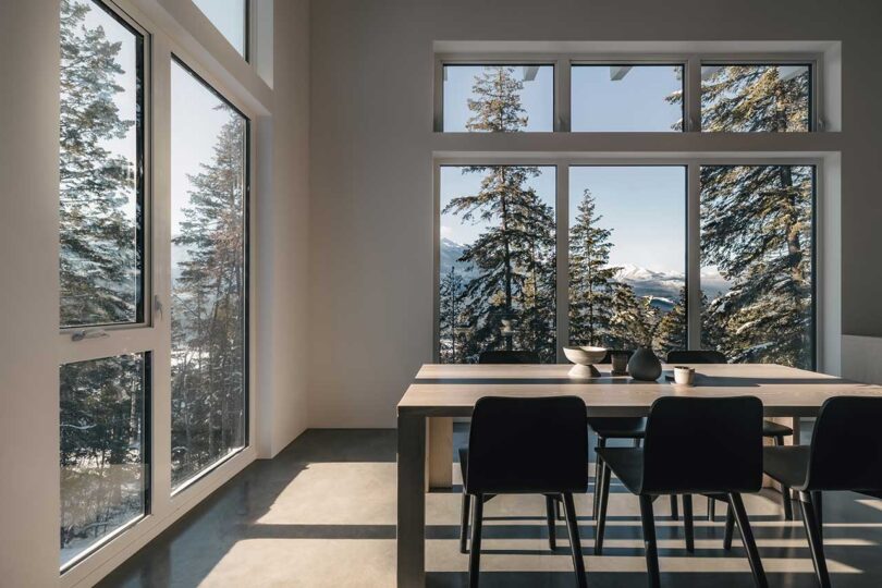 corner interior view of modern dining room with large windows looking out to snowy trees