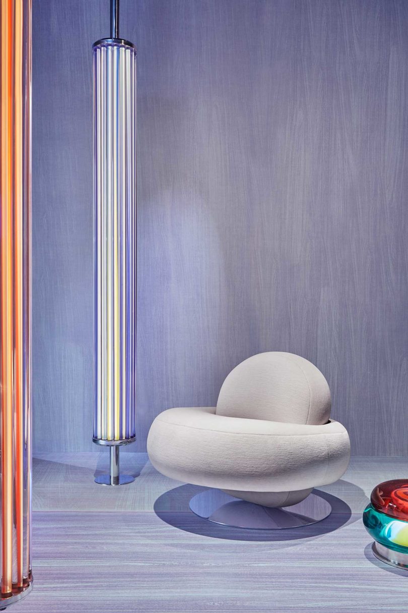 lavender gallery room with space-age silver chair, glowing colorful orbs and cylindrical lights