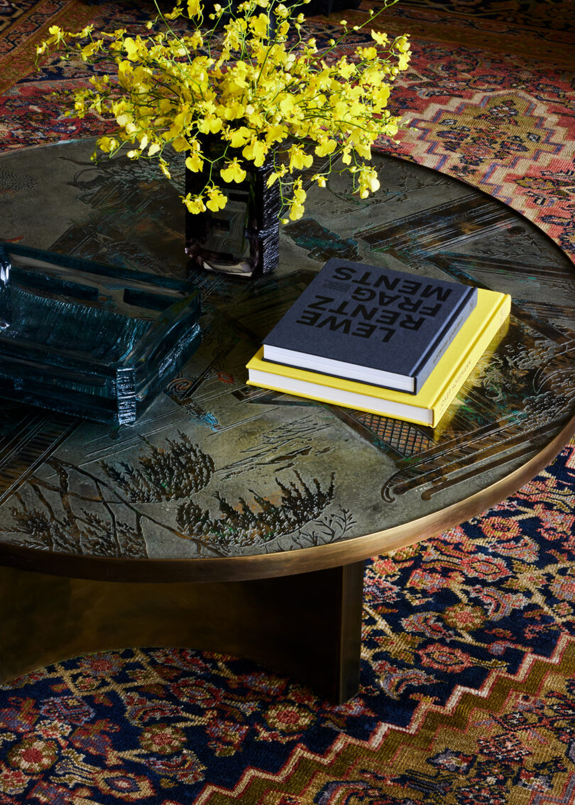 marble coffee table top with a few books and vase of small yellow flowers