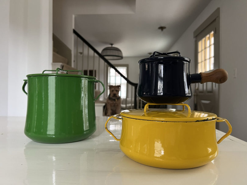 colorful Dansk cookware on a counter with a dog sitting in the background
